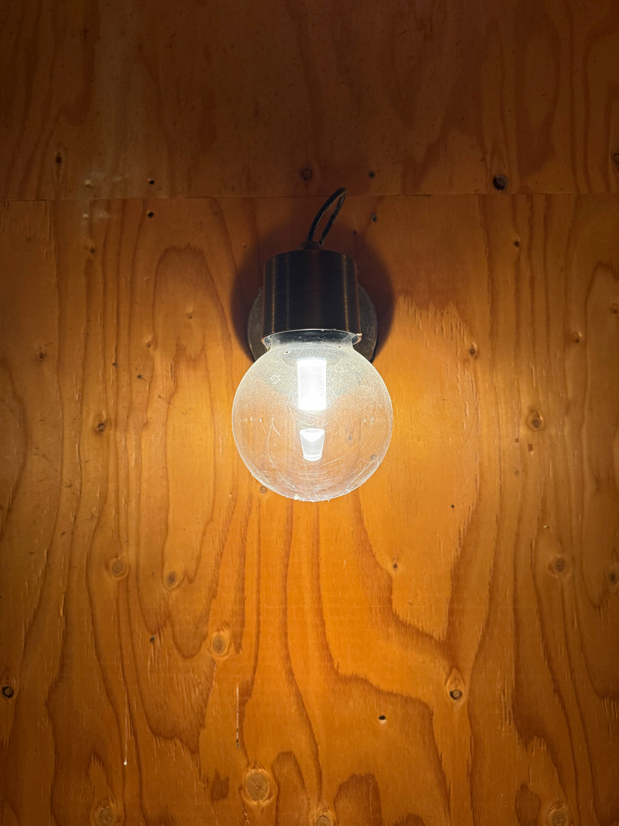 木製の壁に取り付けられた裸電球に、灯りがついている