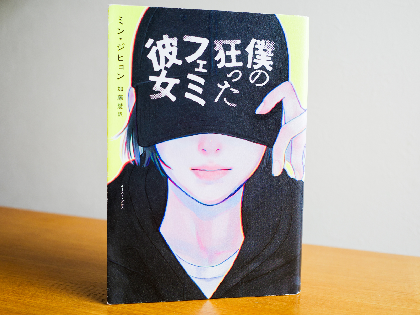 『僕の狂ったフェミ彼女』（ミン・ジヒョン 著 / 加藤慧 翻訳、イースト・プレス、2022年）書影<br>黒いキャップを目深にかぶり、黒いパーカーを着て微かに笑っている若い女性のイラスト