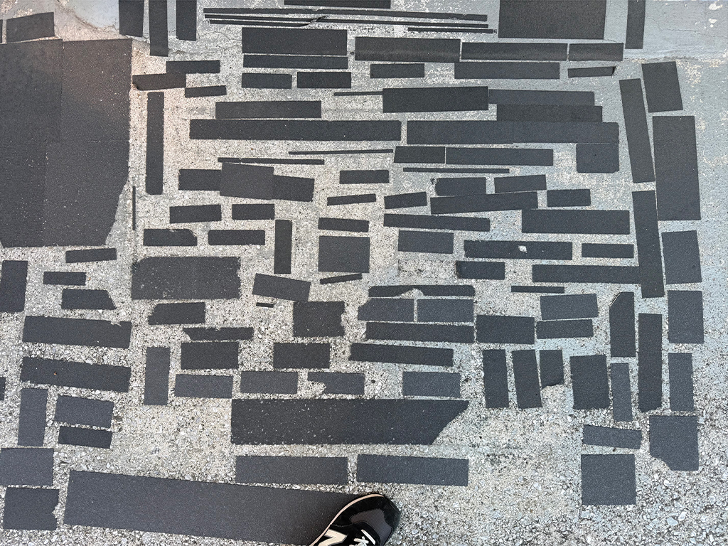 黒と灰色の石畳と、その足元に映る靴の写真